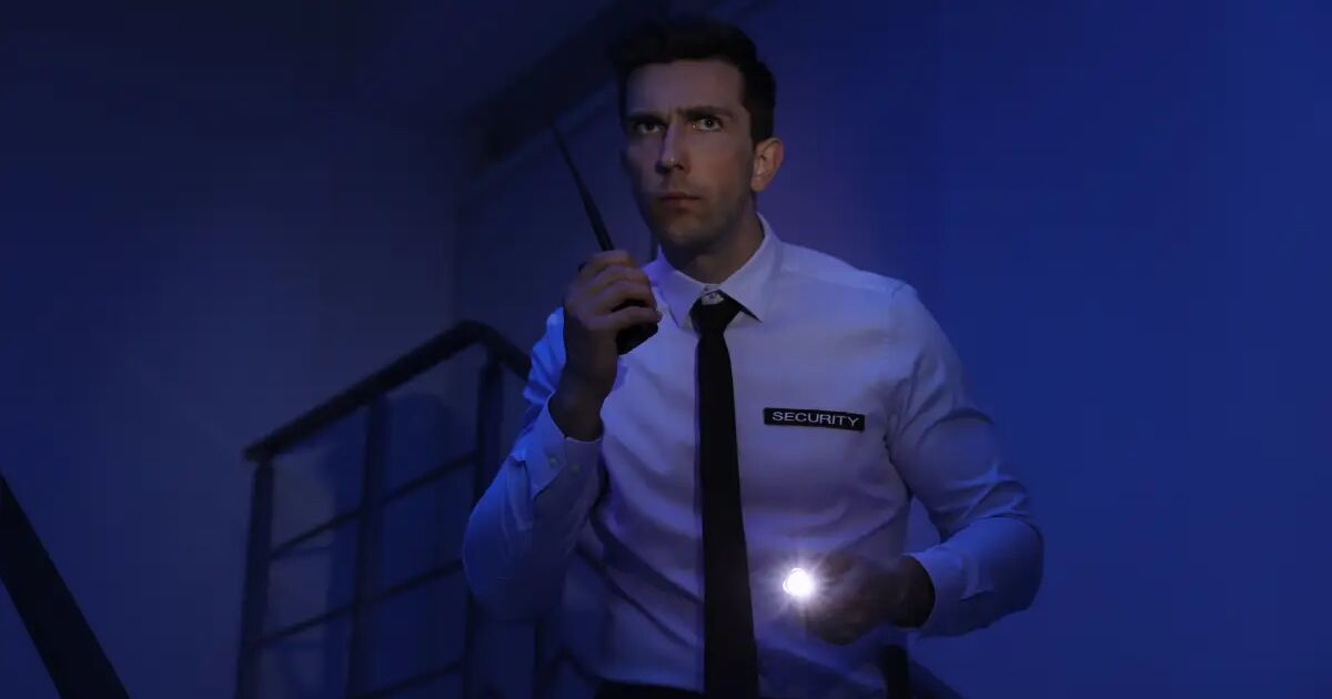 Security guard on a night patrol with a radio and torch